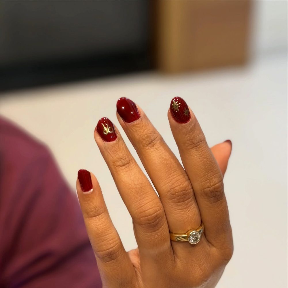 Deep cherry red nails with subtle gold accents